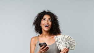 african american woman with a smile on her face holding cash and a phone